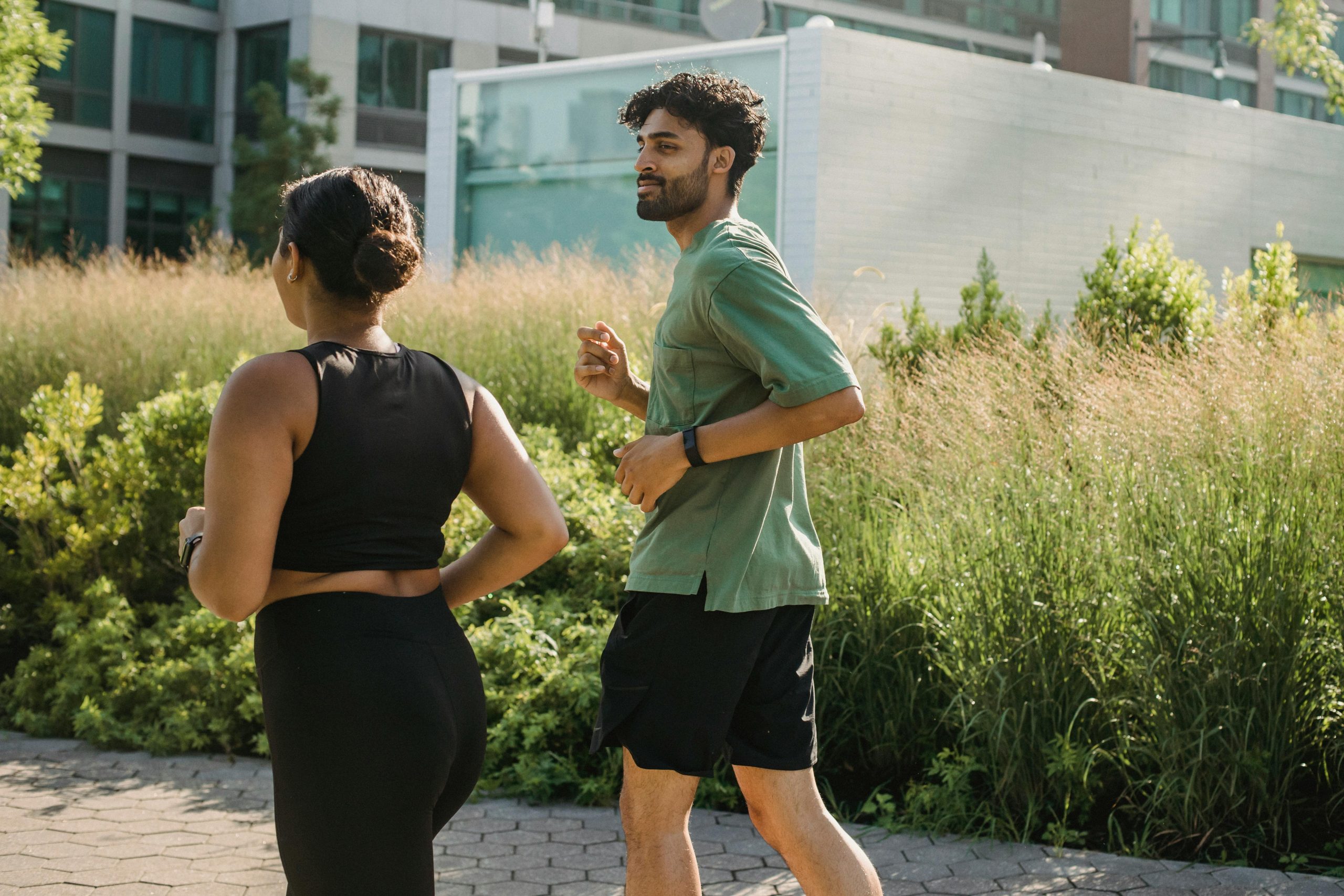 Young couple jogging together in a city park, embracing a healthy lifestyle.
